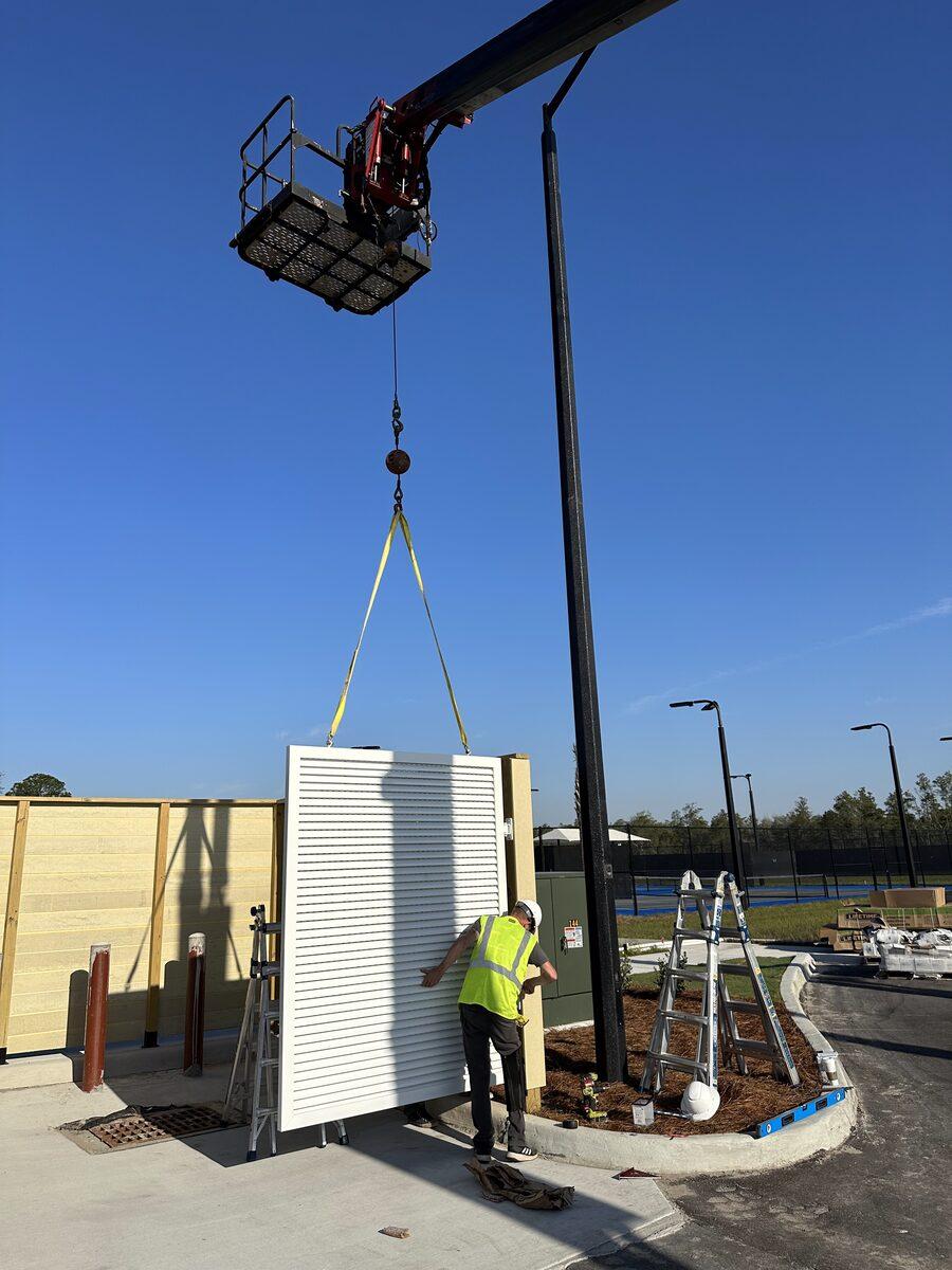 Crane installation of a louvered aluminum equipment screen at Latitude Margaritaville Watersound — by CG Signs