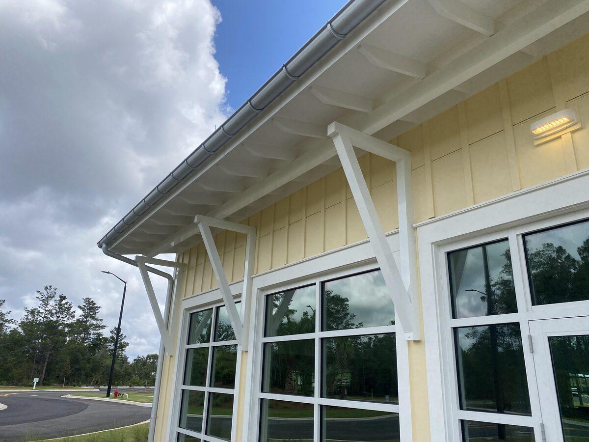 Aluminum architectural canopy brackets and white trim detail on yellow building exterior at Latitude Margaritaville Watersound — by CG Signs