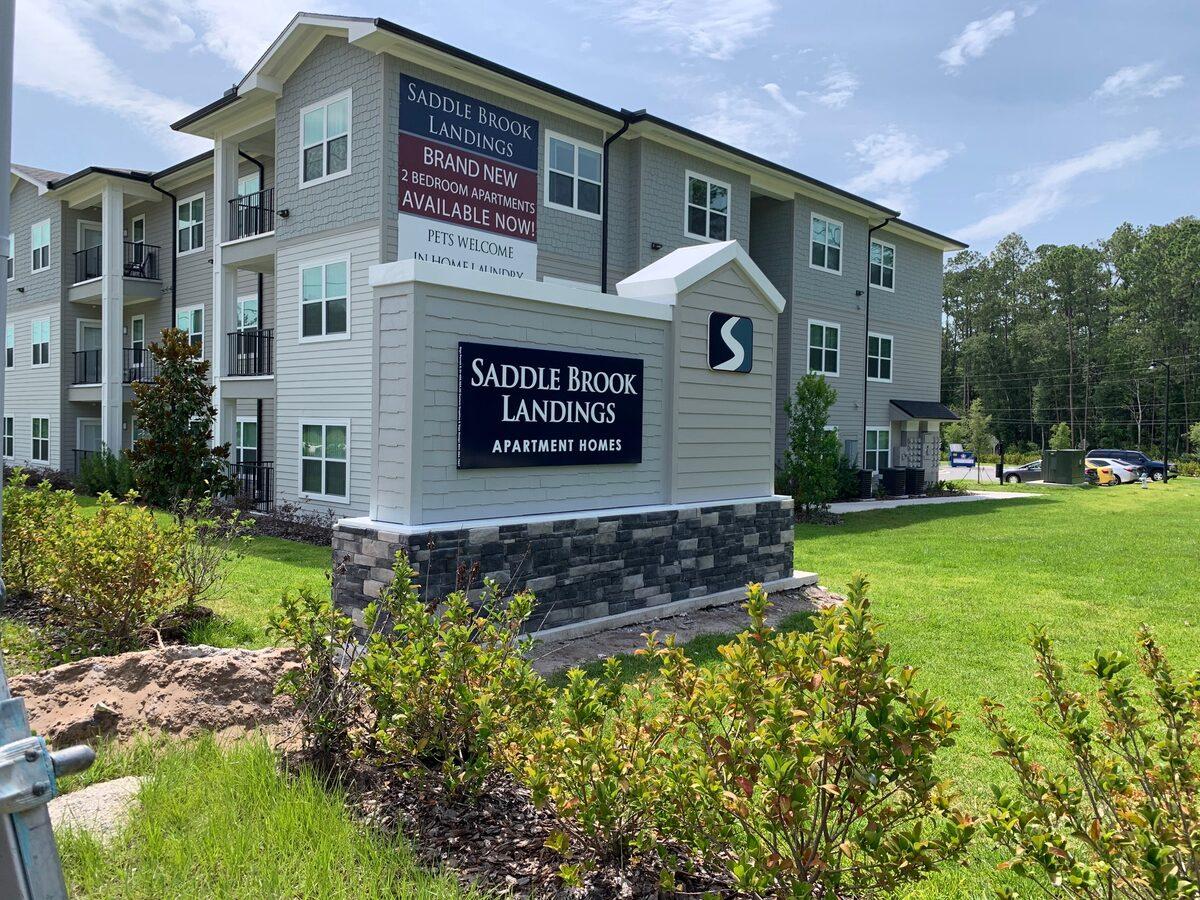 Custom aluminum monument with lap siding, stacked stone base, and aluminum sign panels — CG Signs