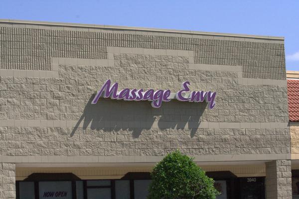 Purple script channel letters for Massage Envy mounted on textured masonry storefront — Custom Graphics & Sign Designs, Jacksonville FL